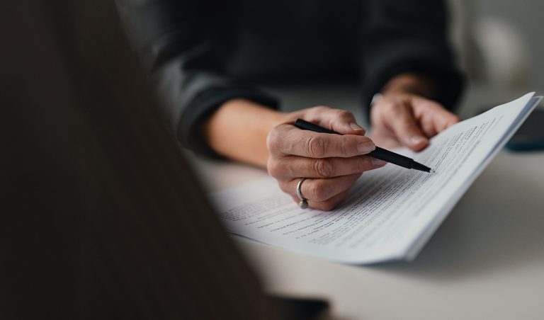 view of a hand with a pen pointing at a paragraph on a paper