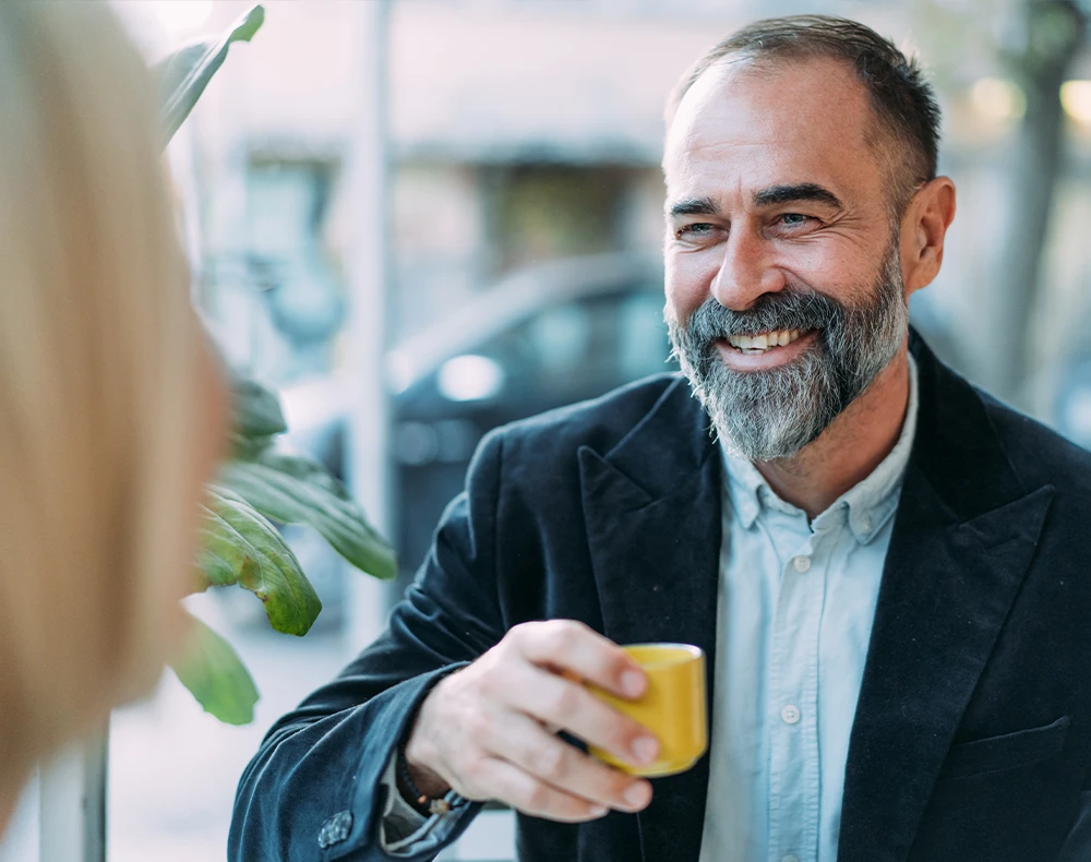business owner in a cafe smiling and holding a cup