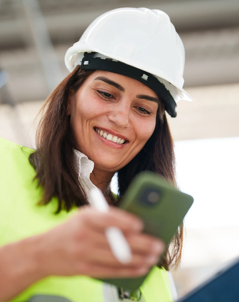 portrait if a female engineer at a construction site looking at her mobile phone