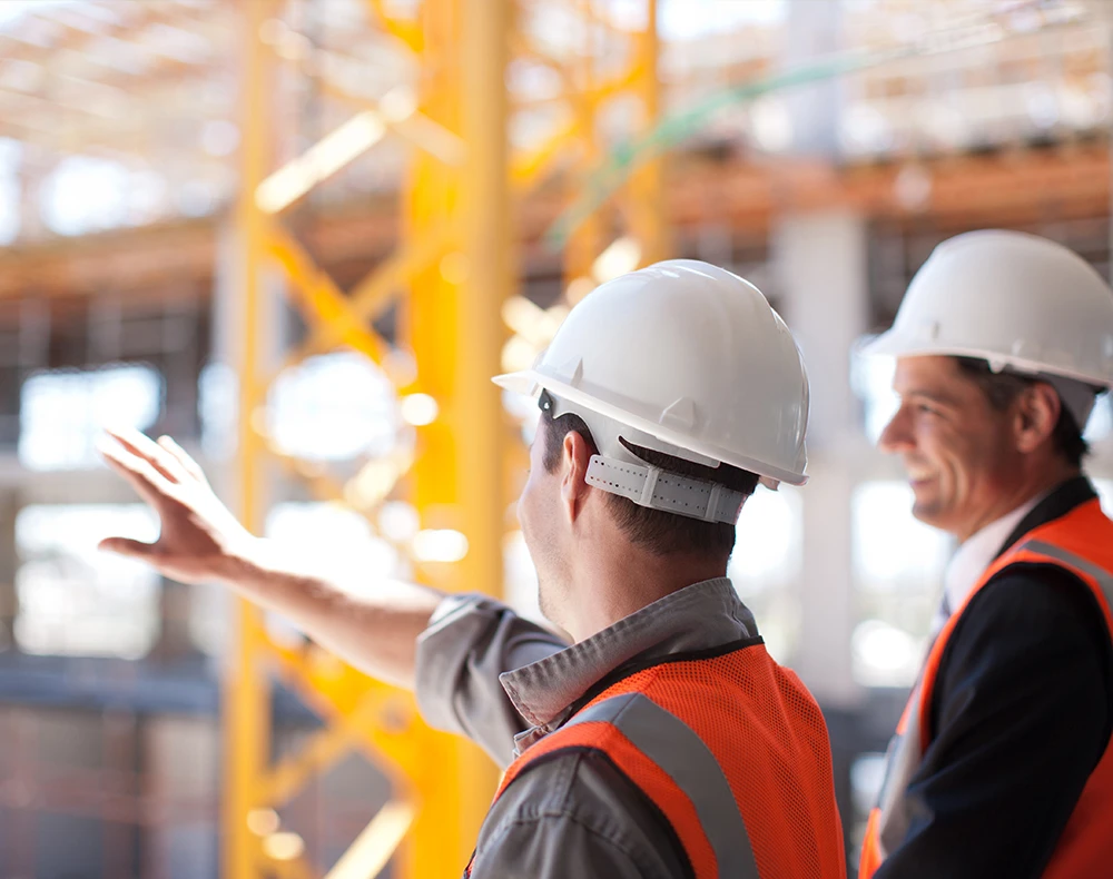 two construction workers in i-v is vests on construction site pointing at something in front of them